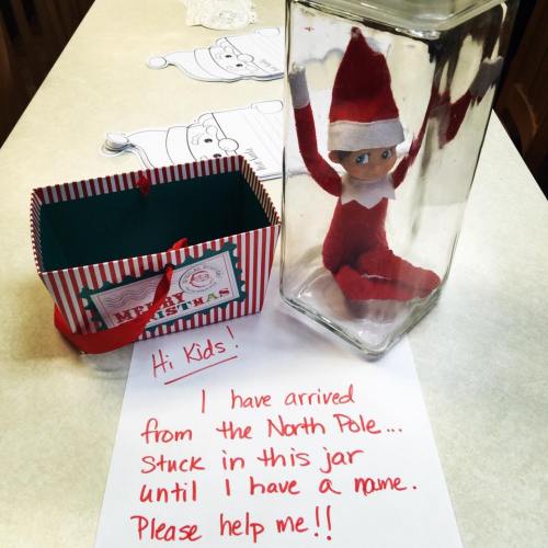 An elf in a jar with a note saying, "Hi Kids! I have arrived from the North Pole... Please help me!"