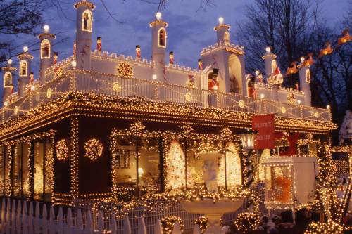 A beautifully decorated house with festive lights and holiday decorations, resembling a castle at dusk.