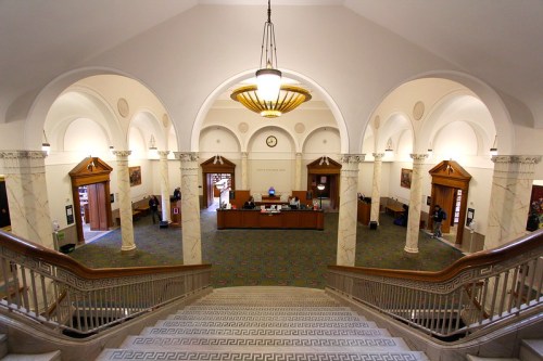 Interior view of a grand staircase leading to a reception area with arches, columns, and decorative lighting.