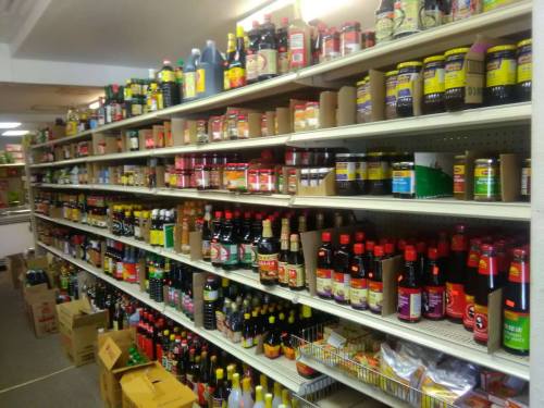 A grocery store aisle filled with various bottles of sauces and condiments on shelves.