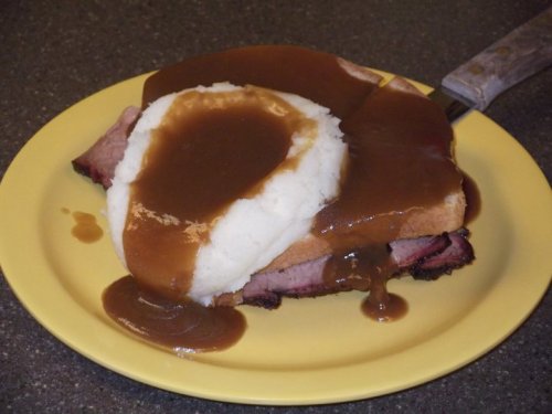 A plate with sliced roast beef, mashed potatoes, and gravy served on bread.