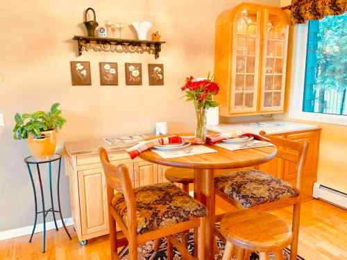 Cozy kitchen nook with a round wooden table, two chairs, floral decor, and a window letting in natural light.