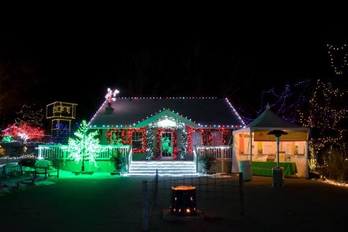 A festive building adorned with colorful lights, surrounded by illuminated trees and decorations, at night.