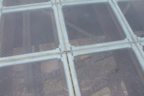 A close-up view of a glass floor panel revealing a metal structure beneath it.