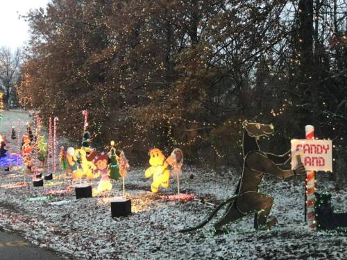 Colorful holiday decorations line a snowy path, featuring characters and lights in a festive display.