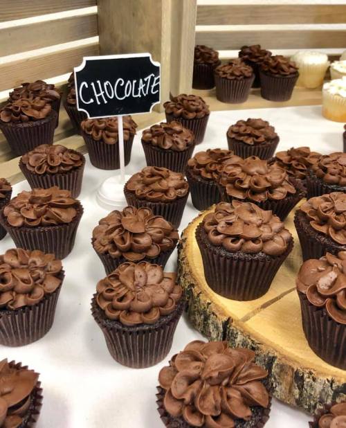 A display of chocolate cupcakes with swirled frosting, next to a sign labeled "Chocolate."