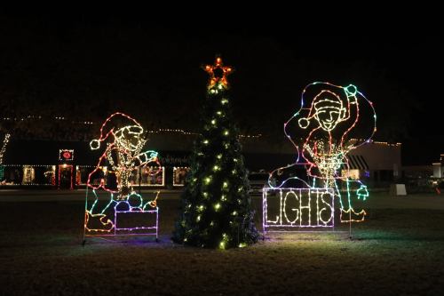 Colorful holiday lights display featuring a Christmas tree and two festive figures in Santa hats.