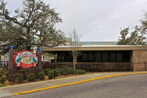 Exterior of Beach Blvd Steamer restaurant, featuring a sign and landscaped entrance on a cloudy day.