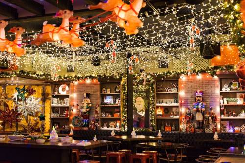 A festive restaurant interior decorated with Christmas lights, ornaments, and playful holiday figures.