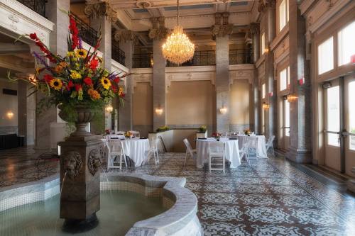 Elegant event space featuring a fountain, floral arrangements, and tables set for dining under a chandelier.
