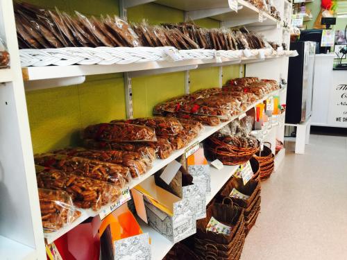 A display of various packaged snacks and treats on shelves, including cookies and pretzels, in a store setting.