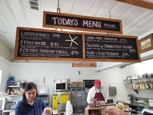 A chalkboard menu displays daily specials, including lobster rolls, crab cake sandwich, and shrimp tacos, in a casual eatery.