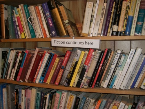 A bookshelf filled with various books, labeled "Fiction continues here" in the center.