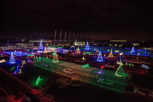 Aerial view of a festive light display featuring colorful trees and decorations in a dark night setting.