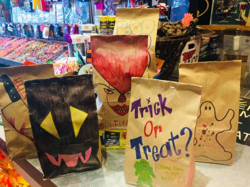 A display of decorated paper bags for Halloween, featuring spooky designs and the phrase "Trick or Treat?" in colorful letters.