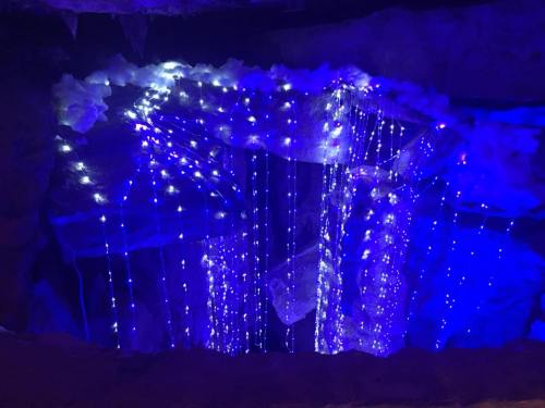 A cave-like space illuminated with blue and white string lights, creating a shimmering waterfall effect.