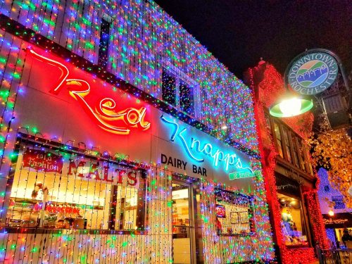 A brightly lit dairy bar with colorful holiday lights and a neon sign reading "Red Knapp's" in downtown Rochester.