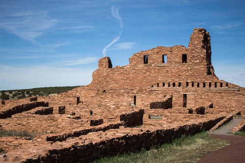 Ancient stone ruins under a blue sky, showcasing remnants of a historical structure in a desert landscape.