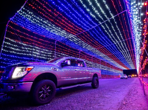 A truck drives through a colorful tunnel of red, white, and blue lights at night.