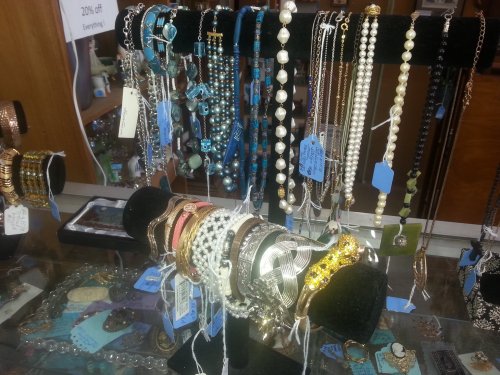 A display of various necklaces and bracelets on stands, with price tags and a sign indicating a 20% discount.