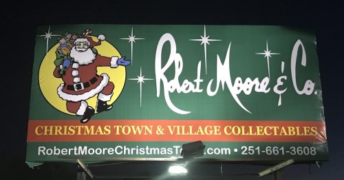 Billboard for Robert Moore & Co. featuring Santa Claus and promoting Christmas town and village collectibles.
