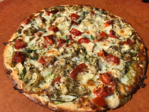 A freshly baked pizza topped with vegetables, cheese, and herbs on a golden crust.