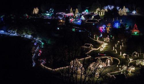 Aerial view of a festive landscape illuminated with colorful Christmas lights and decorations.
