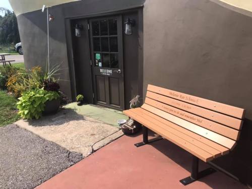 A welcoming entrance with a bench and potted plants beside a door, inviting visitors to the location.