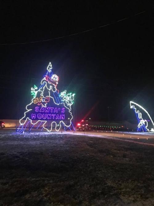 Colorful holiday lights display featuring a large Christmas tree with "Santa's Mountain" sign at night.