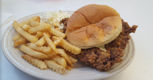 A plate with a fried chicken sandwich, crinkle-cut fries, and a side of coleslaw.