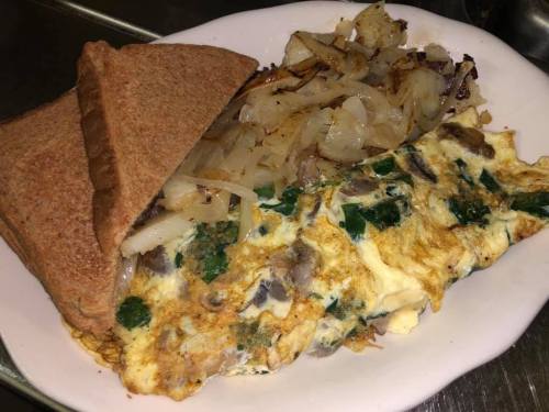 A plate with a vegetable omelette, sautéed onions, and two slices of toasted whole grain bread.