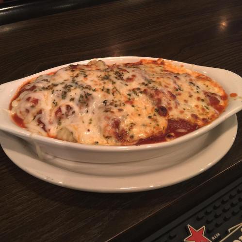 A baked pasta dish topped with melted cheese and marinara sauce, served in a white dish.