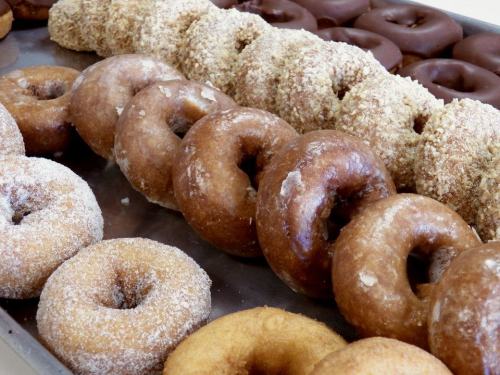 A tray of assorted donuts, including glazed, chocolate-covered, and crumb-topped varieties.