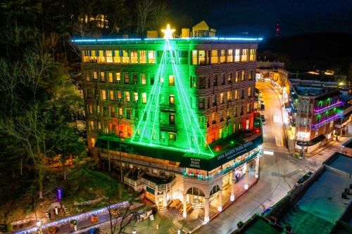 A hotel decorated with bright green lights shaped like a Christmas tree, topped with a star, against a night sky.