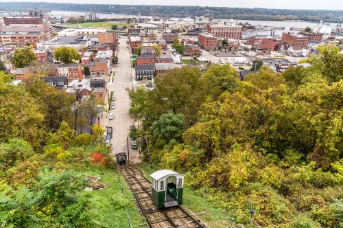 A scenic view of a city with a funicular railway descending a hillside, surrounded by trees and buildings.