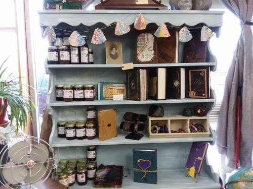 A blue wooden shelf displays jars, books, and handmade items, decorated with colorful paper garlands.