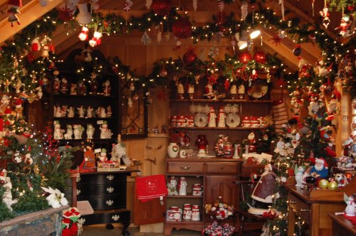 A cozy holiday-themed room filled with festive decorations, ornaments, and Christmas collectibles.