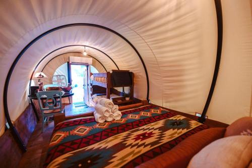 Cozy interior of a glamping tent with a bed, bunk beds, and rustic decor featuring a colorful patterned blanket.