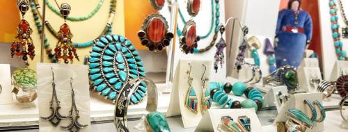 A display of colorful jewelry, including earrings, necklaces, and bracelets, featuring turquoise and other gemstones.
