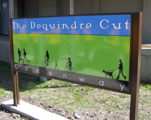 Sign for The Dequindre Cut Greenway featuring silhouettes of people walking, biking, and a dog.