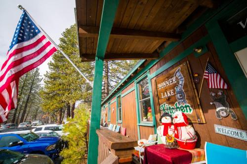 A cozy cabin with a porch, featuring a flag, holiday decorations, and a sign for Donner Lake Kitchen.