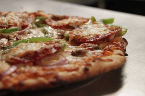 A close-up of a freshly baked pizza topped with pepperoni, green peppers, onions, and melted cheese.