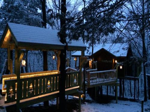 A cozy cabin in a snowy forest, illuminated with warm lights, surrounded by trees and a serene winter atmosphere.