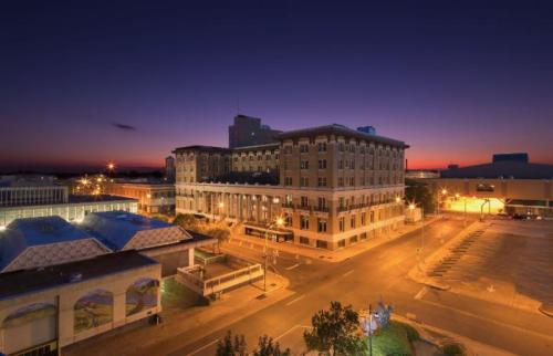A cityscape at dusk featuring a historic building with warm lights and a colorful sky in the background.