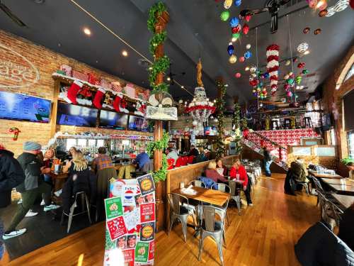 A festive restaurant interior decorated with holiday ornaments, garlands, and patrons enjoying their meals.