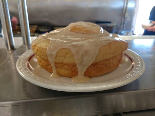 A fluffy, golden pastry topped with creamy icing, sitting on a white plate.
