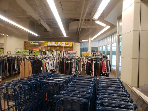 A clothing store interior with racks of men's clothing and shopping carts in the foreground.