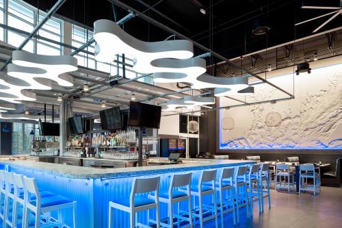 Modern bar interior with illuminated blue accents, unique ceiling lights, and a stylish counter.