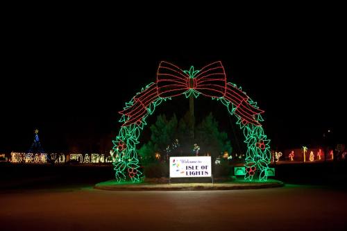 A festive archway adorned with red and green lights, welcoming visitors to the "Isle of Lights" display at night.