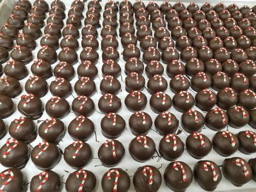 A large tray filled with rows of chocolate-covered candies topped with red and white striped decorations.